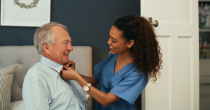 Young nurse assisting elderly patient with getting dressed